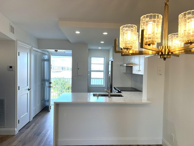 kitchen with a notable chandelier, dark hardwood / wood-style floors, white cabinetry, and kitchen peninsula