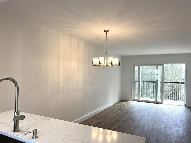 interior space with light stone counters, dark hardwood / wood-style flooring, pendant lighting, and a notable chandelier