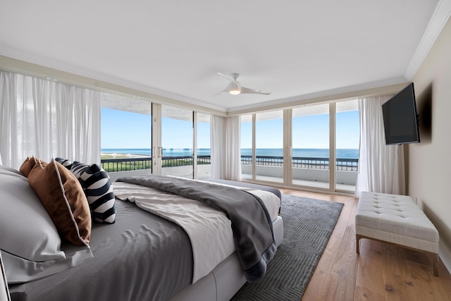 bedroom with hardwood / wood-style floors, crown molding, ceiling fan, access to exterior, and a wall of windows