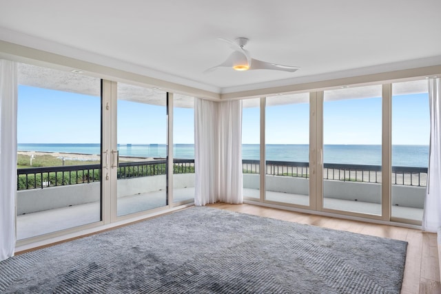 unfurnished sunroom with a view of the beach, a water view, and ceiling fan