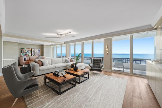 living room with ceiling fan, a water view, light wood-type flooring, and plenty of natural light