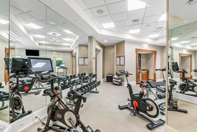 exercise room with a drop ceiling, a raised ceiling, and carpet flooring