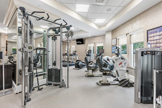 gym featuring a paneled ceiling and a raised ceiling