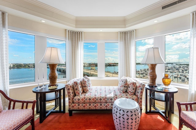 sunroom featuring a raised ceiling, a water view, and a wealth of natural light