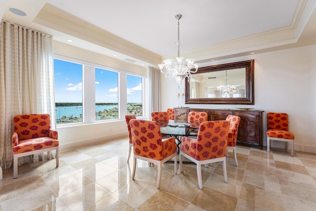 dining space featuring a water view, crown molding, a chandelier, and a raised ceiling