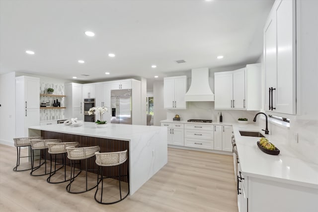 kitchen featuring appliances with stainless steel finishes, a center island, custom exhaust hood, sink, and a breakfast bar area