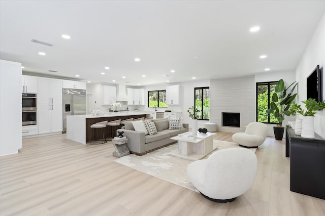 living room featuring a large fireplace and light wood-type flooring