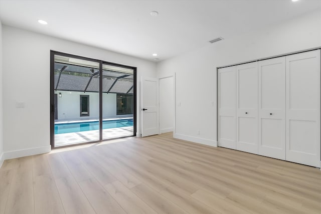 unfurnished bedroom featuring light hardwood / wood-style floors, access to exterior, and a closet