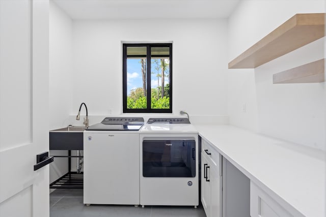 clothes washing area with washing machine and dryer, cabinets, and light tile patterned flooring