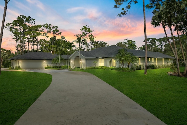 ranch-style house with a garage and a lawn