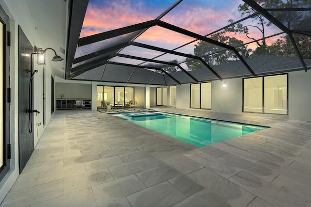 pool at dusk featuring a patio area and a lanai