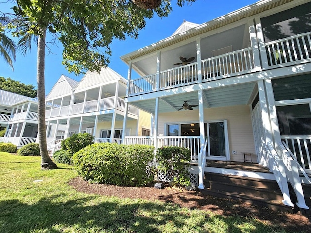 rear view of house featuring a yard, a balcony, and ceiling fan