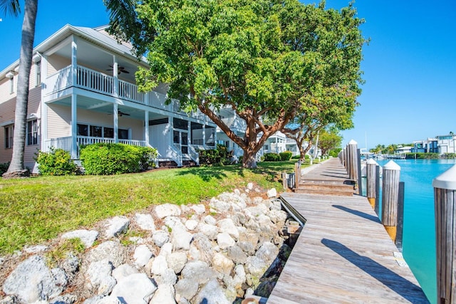 view of dock featuring a water view, a balcony, and a yard