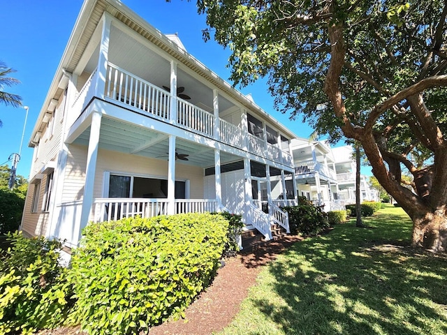 back of property with a balcony, ceiling fan, and a lawn