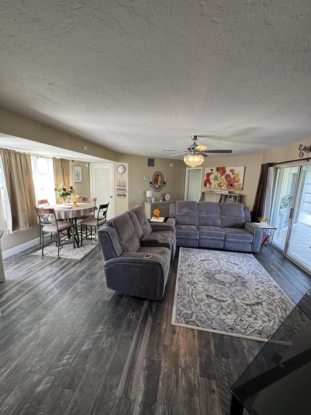 living room featuring ceiling fan, dark wood-type flooring, and a textured ceiling