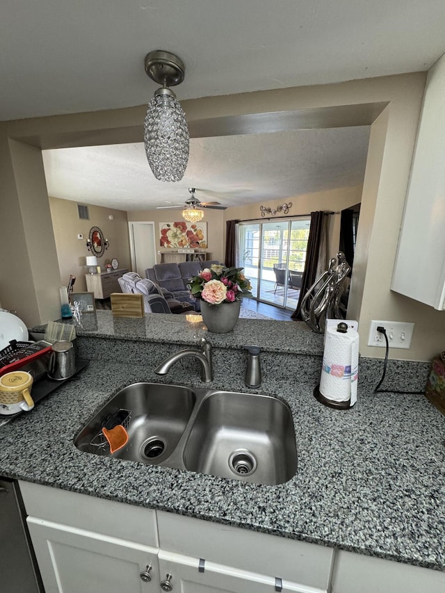 kitchen featuring white cabinetry, ceiling fan, dark stone countertops, and sink