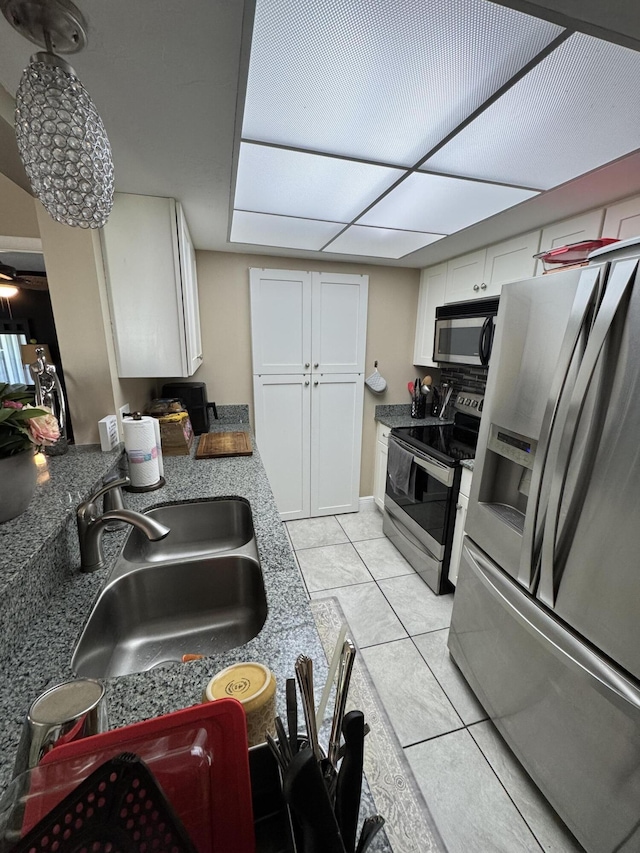 kitchen featuring white cabinets, appliances with stainless steel finishes, light tile patterned floors, and sink