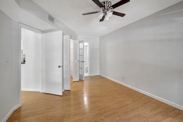 spare room with ceiling fan, a textured ceiling, and light hardwood / wood-style flooring