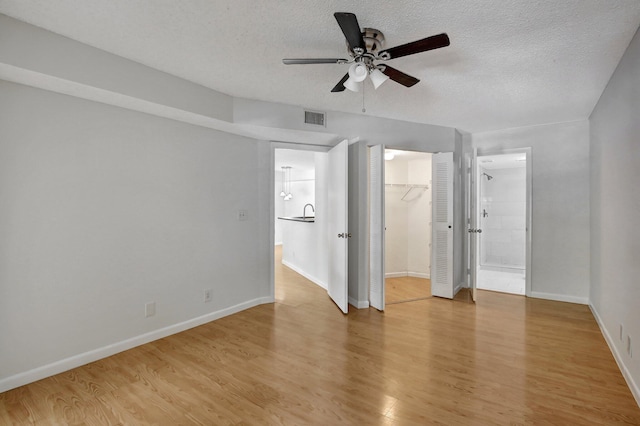 spare room featuring a textured ceiling, light hardwood / wood-style flooring, and ceiling fan