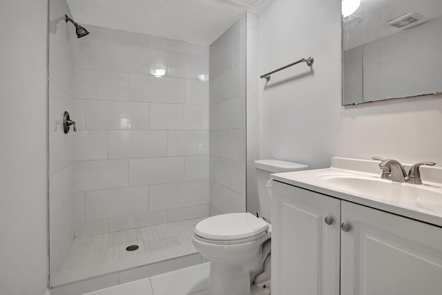 bathroom featuring a tile shower, vanity, and toilet