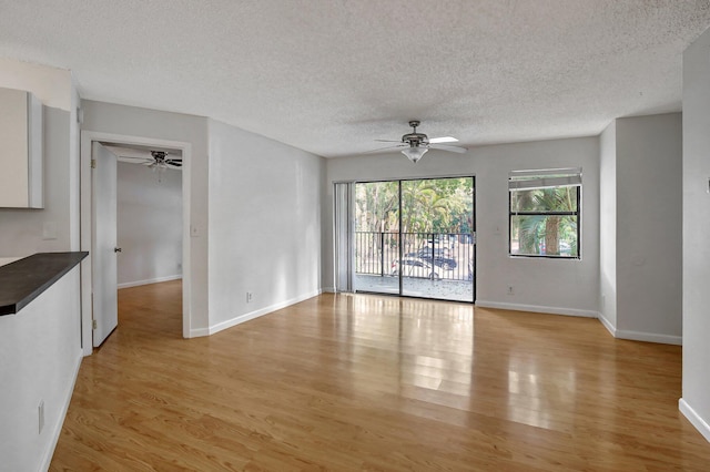 empty room with ceiling fan, light hardwood / wood-style flooring, and a textured ceiling