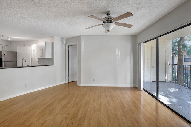 unfurnished living room with ceiling fan, sink, a textured ceiling, and light hardwood / wood-style flooring