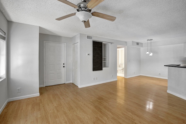 unfurnished living room with ceiling fan, light hardwood / wood-style floors, and a textured ceiling