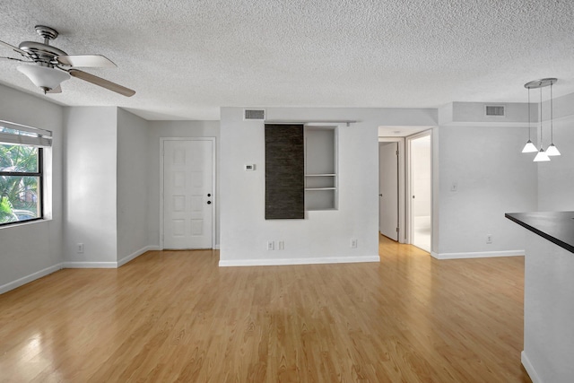 unfurnished living room with a textured ceiling, ceiling fan with notable chandelier, and light wood-type flooring