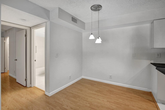 unfurnished dining area with hardwood / wood-style floors and a textured ceiling