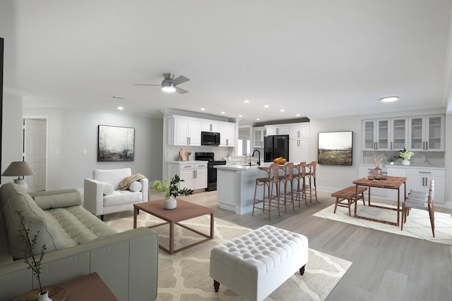 living room with ceiling fan, crown molding, and light hardwood / wood-style flooring