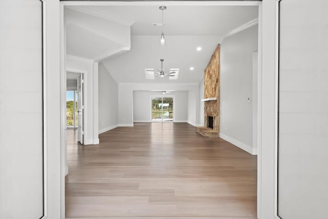 unfurnished living room featuring lofted ceiling, light hardwood / wood-style flooring, ceiling fan, ornamental molding, and a fireplace