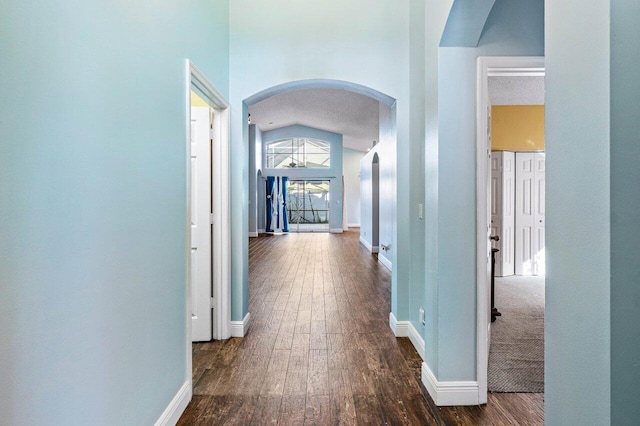 hallway featuring dark wood-type flooring and high vaulted ceiling