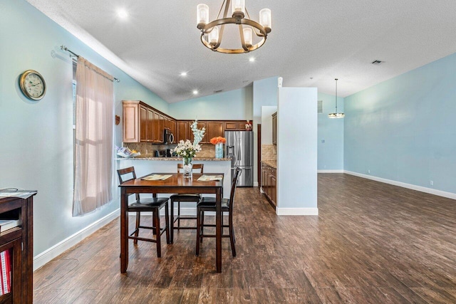 dining room featuring a textured ceiling, a chandelier, dark wood-type flooring, and vaulted ceiling