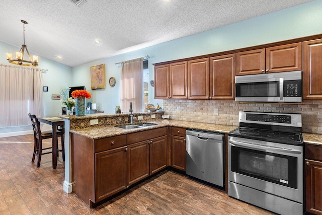 kitchen with sink, light stone countertops, kitchen peninsula, stainless steel appliances, and a chandelier