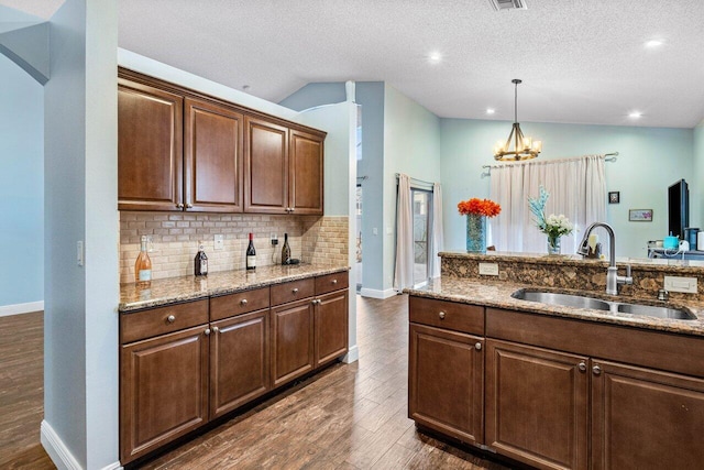 kitchen with a textured ceiling, light stone countertops, sink, and lofted ceiling