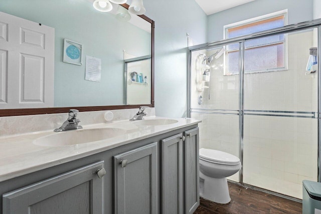 bathroom with wood-type flooring, vanity, toilet, and an enclosed shower