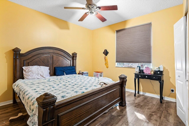 bedroom with a textured ceiling, ceiling fan, and dark wood-type flooring