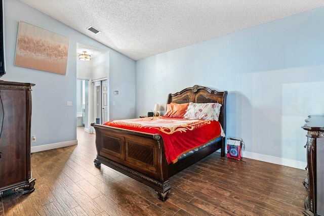 bedroom with vaulted ceiling, dark wood-type flooring, and a textured ceiling