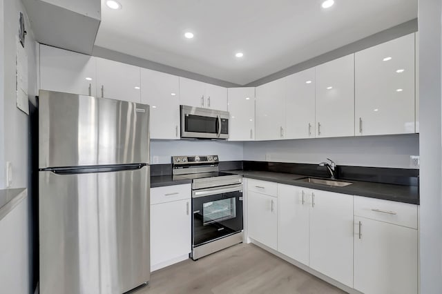 kitchen featuring sink, white cabinetry, stainless steel appliances, and light wood-type flooring