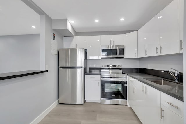 kitchen featuring white cabinets, sink, stainless steel appliances, and light hardwood / wood-style flooring