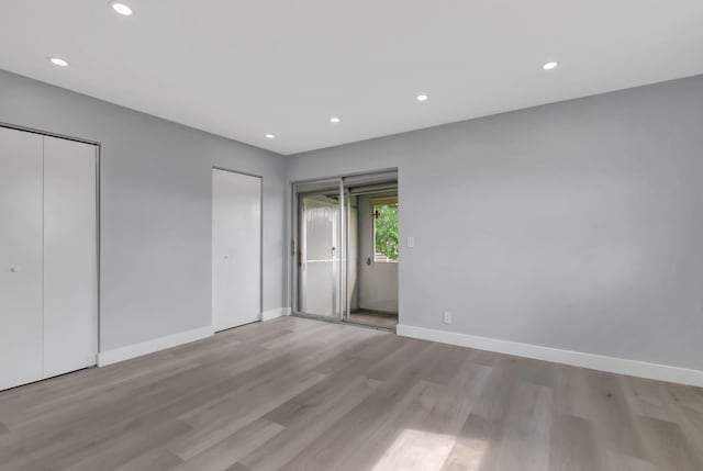 unfurnished bedroom featuring light hardwood / wood-style floors and two closets