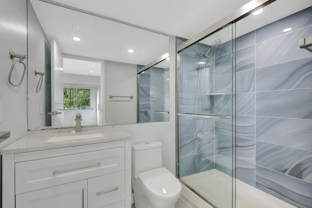 bathroom with a shower with door, vanity, and toilet