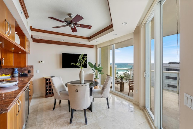 dining area with a tray ceiling, ceiling fan, and crown molding