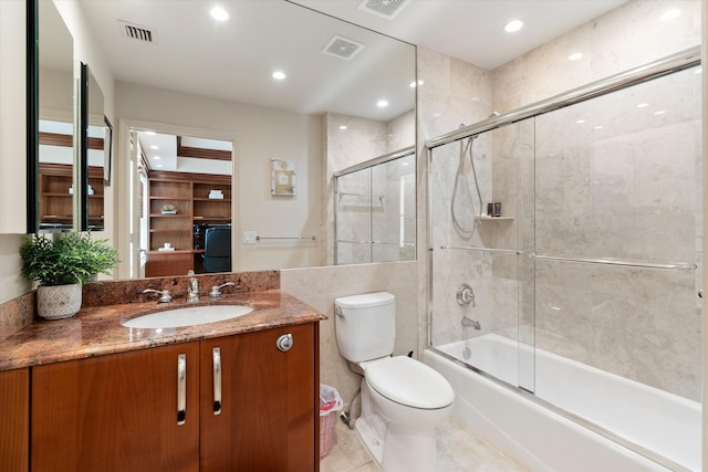 full bathroom featuring tile patterned floors, vanity, tile walls, enclosed tub / shower combo, and toilet