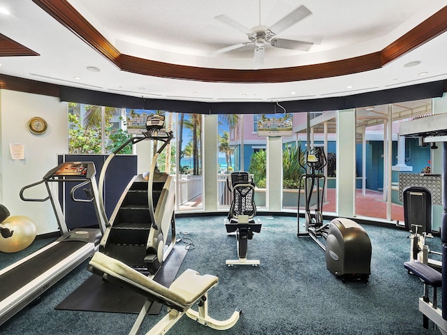 workout area with ceiling fan, a raised ceiling, and crown molding