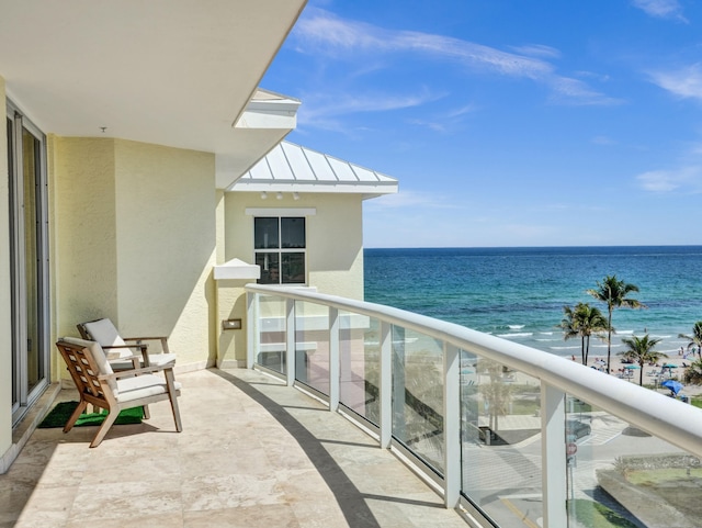 balcony with a water view and a view of the beach