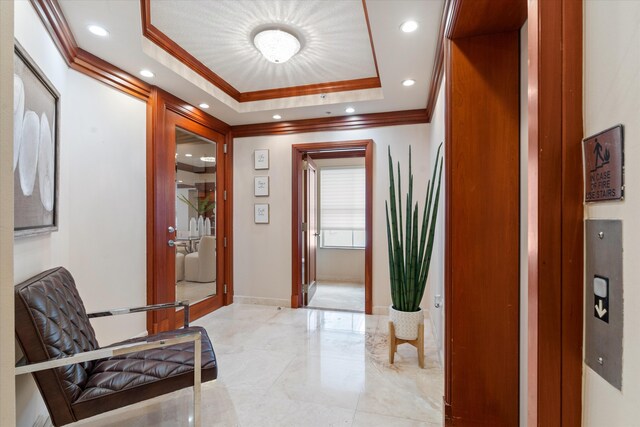 corridor featuring a raised ceiling and ornamental molding