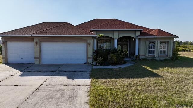 ranch-style home with a garage and a front lawn