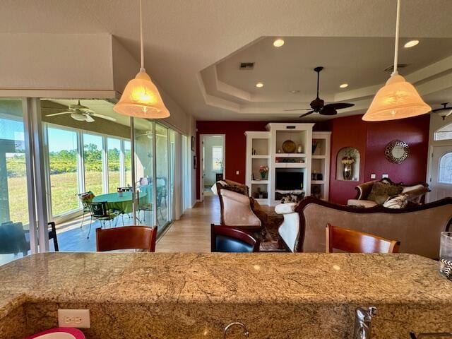 kitchen featuring a tray ceiling, decorative light fixtures, and light wood-type flooring