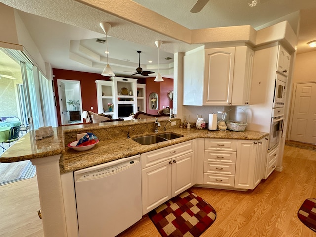 kitchen featuring sink, hanging light fixtures, a raised ceiling, white appliances, and white cabinets